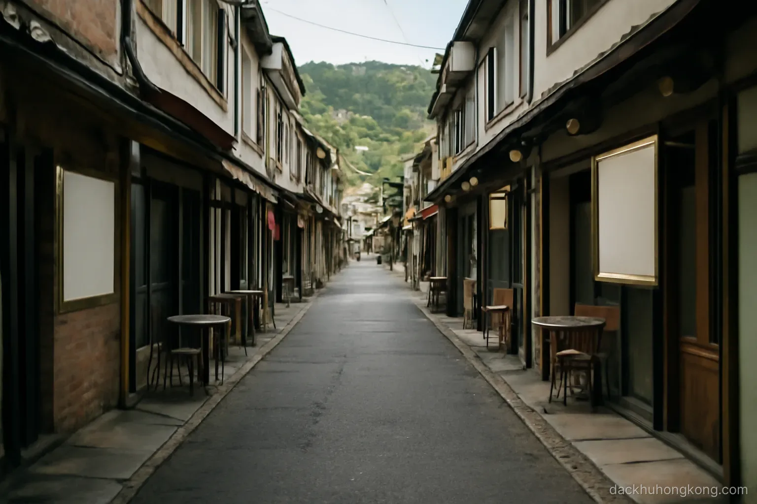 a narrow street packed with small shops and diners with green hills visible at the far end