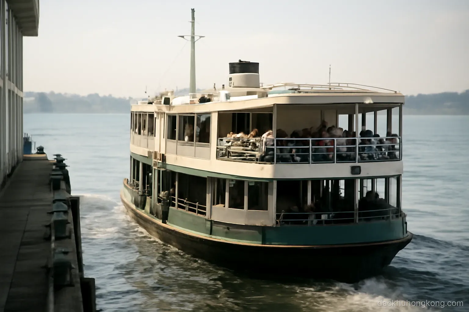 a double deck ferry pulling away from a pier with commuters seated on the open upper deck